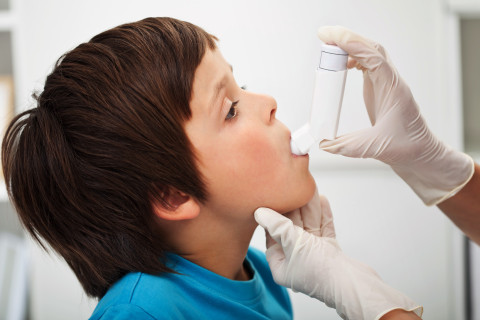 Aikuinen auttaa lasta käyttämään astmapiippua.