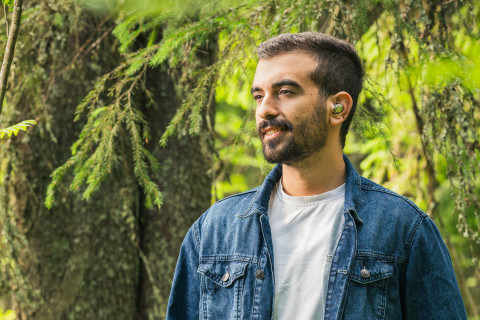 Mies kuuntelee verkkokurssia metsässä