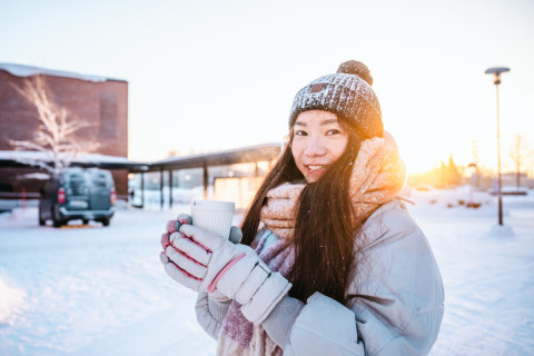 Student in winter ourdoors, holding a coffee cup