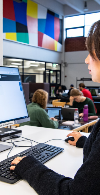 Opiskelija käyttää UEF-Primoa kirjaston tietokoneella.