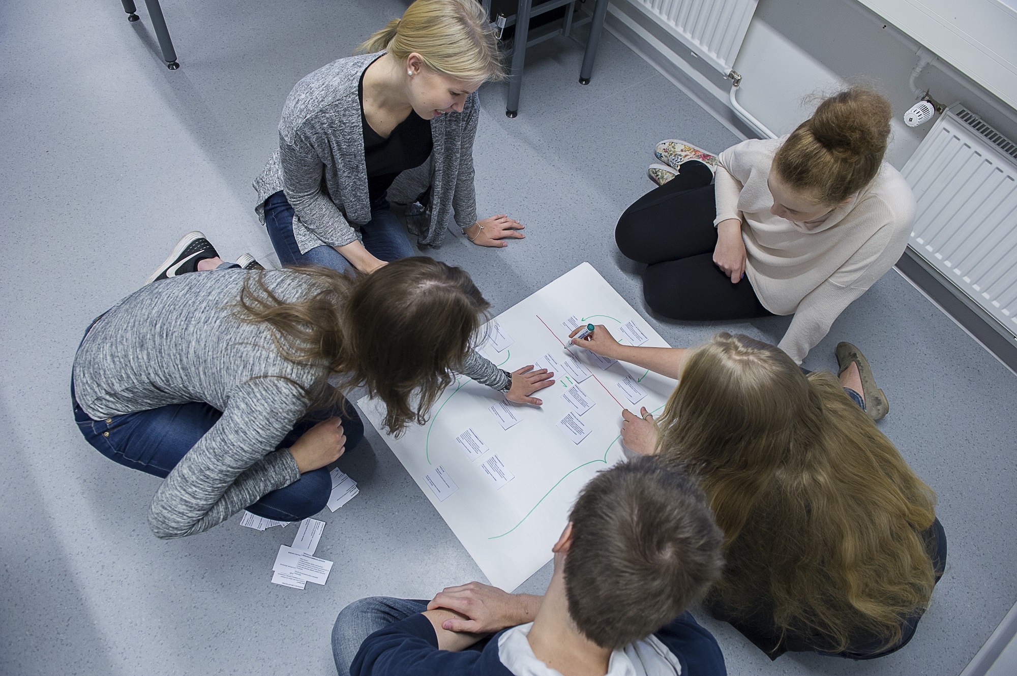 Viisi opiskelijaa tekee ryhmätyötä.