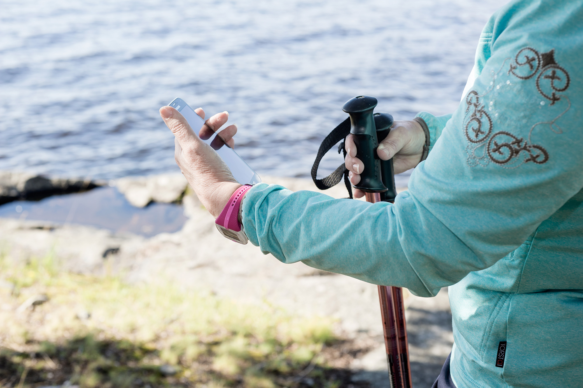 Person with Nordic walking poles looking at mobile phone