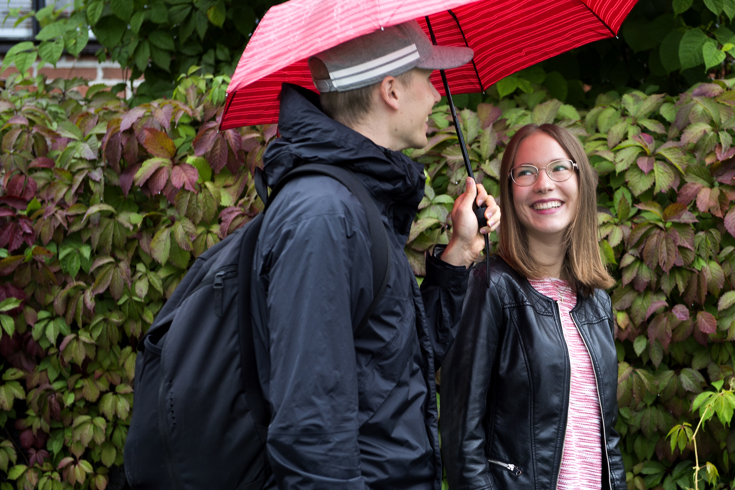 Opiskelijat kävelevät kampuksen ulkopuolella sateenvarjon kanssa