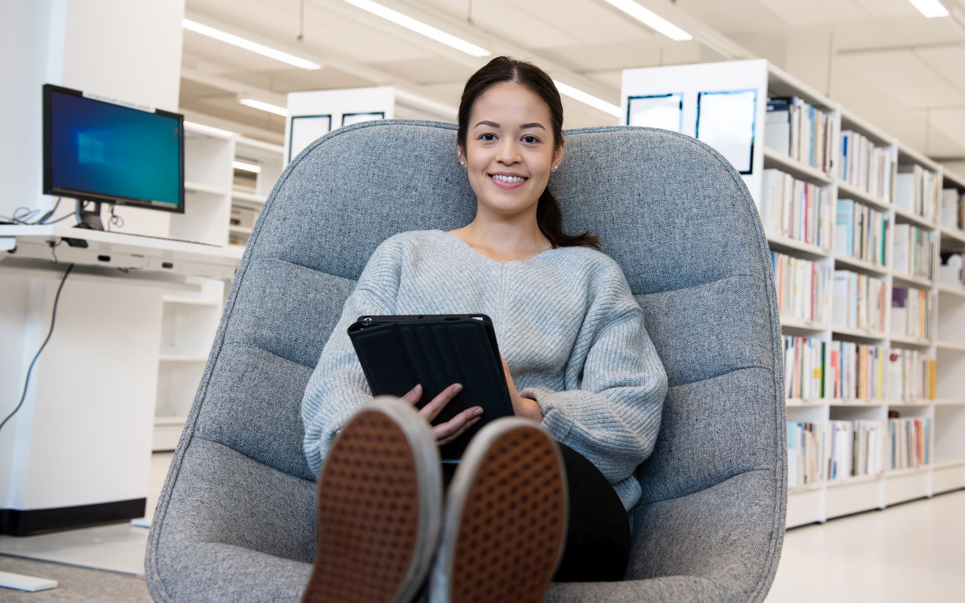 Opiskelija lukee kirjaston salissa.