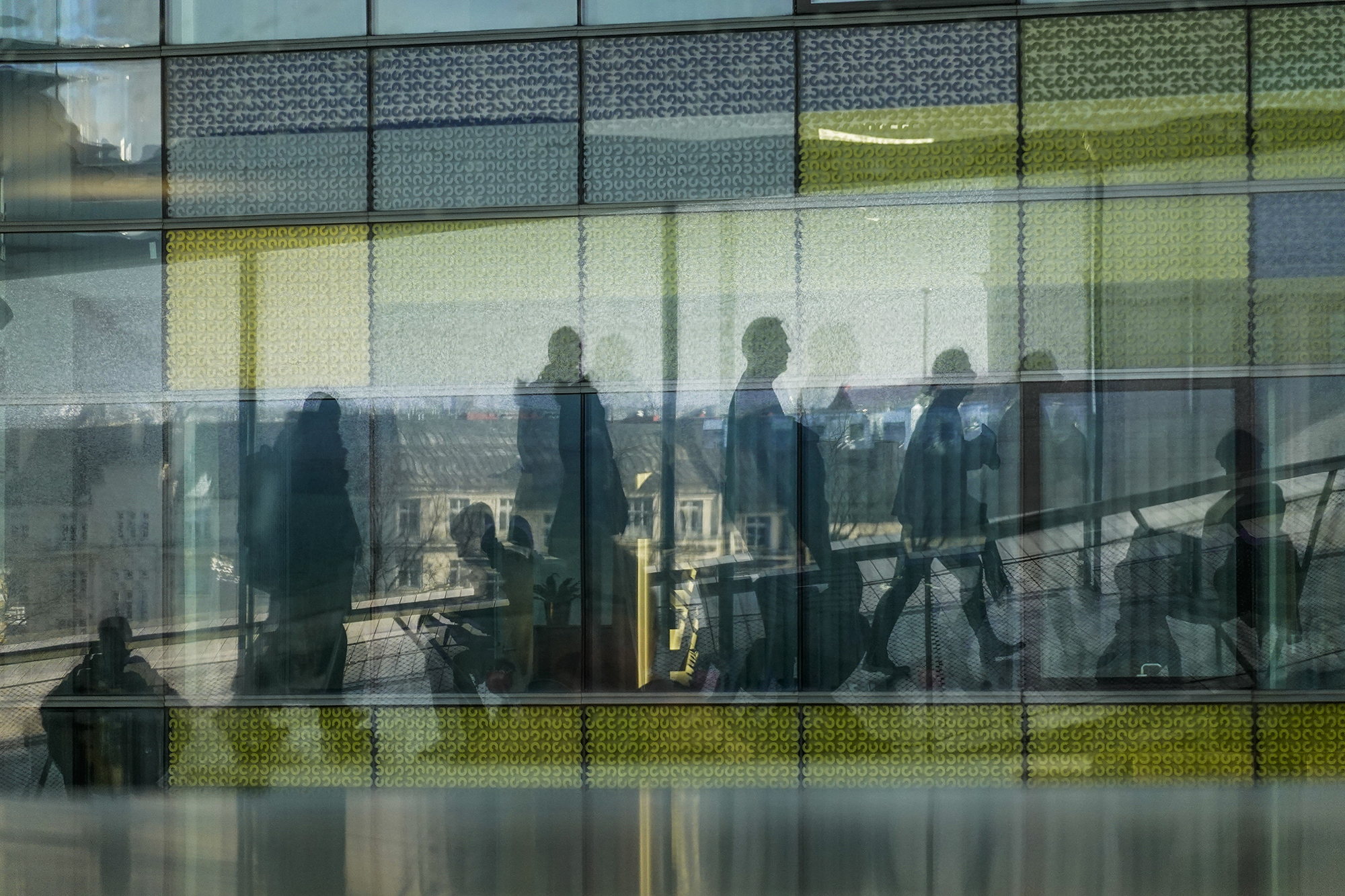 Ihmishahmoja kävelee kaupunkimaisemassa.