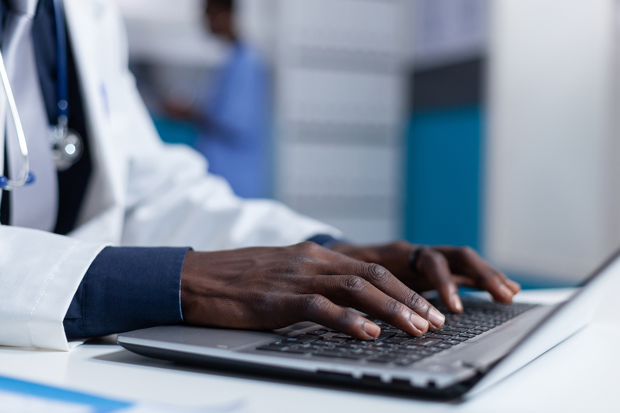 Lääkärin kädet tietokoneen näppäimistöllä.