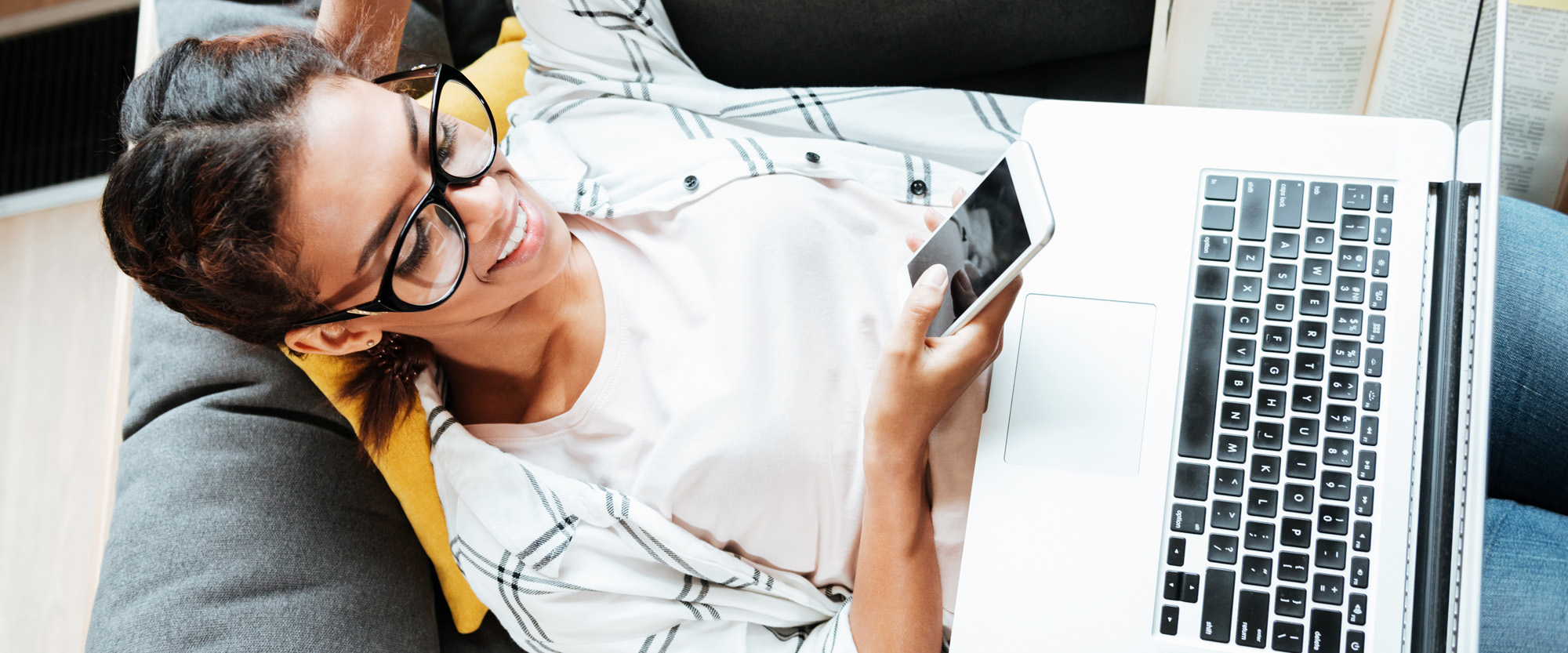 Nainen työskentelee kannettavalla tietokoneella ja matkapuhelimella.