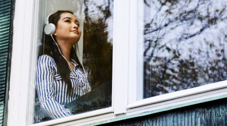 Student with headphones sitting by a window.