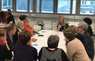 Ihmisiä istumassa pöydän ympärillä tekemässä ryhmätyötä.