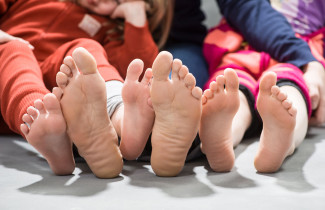 perhe istuu lattialla paljaat jalkapohjat näkyvillä