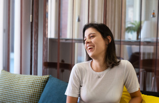 Young woman sitting on a sofa, laughing to something outside the photo.