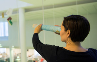 Nainen tähystää kaukaisuuteen rullattu kartta kaukoputkenaan.