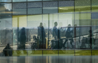 Ihmishahmoja kävelee kaupunkimaisemassa.