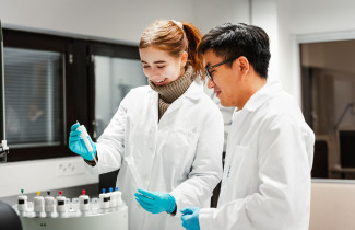 Kaksi tutkijaa työskentelee näytteen parissa kemian laboratoriossa.