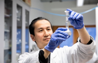 Tutkija pitelee käsissään näytettä laboratoriossa.