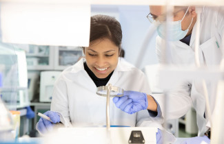 Vanhempi tutkija opastaa nuori tutkijaa laboratoriossa.