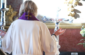 Pappi suorittamassa jumalanpalvelusta kirkon alttarilla.