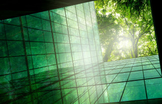 Alhaaltapäin kuvattu lasiseinäinen rakennus, puita pilkistää ylhäältä.