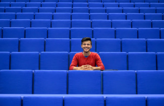 Opiskelija istumassa keskellä tyhjää auditoriota