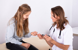 Doctor measuring child&#039;s blood sugar.