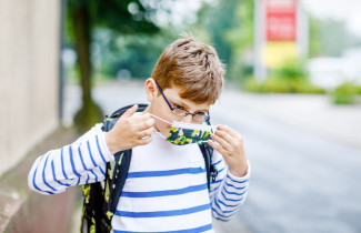 Koululainen laittaa suojamaskia kasvoille.