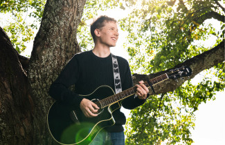 UEF-lähettiläs Konsta Kinnunen kitara kädessä