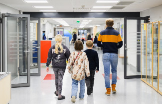 Alakoulun oppilaat kävelemässä opettajan kanssa käytävällä.