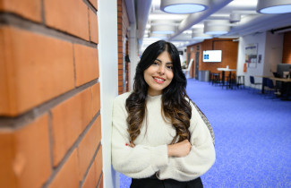 Student standing in a corridor and smiling