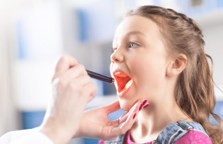 Lääkäri tutkii lapsen kurkkua.