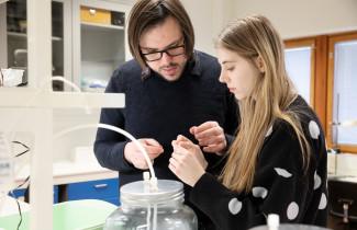 Two people in a laboratory-like environment examining something together.