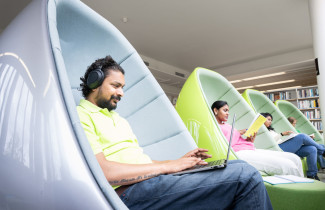 Opiskelijoita lukemassa kirjaa kuplatuoleissa; Students reading a book in bubble chairs.
