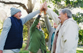 Neljä ikäihmistä liittää kädet yhteen päiden päällä.