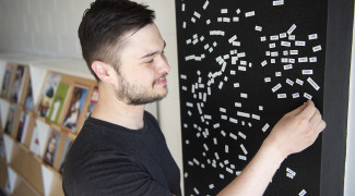 Young man playing with magnetic words.