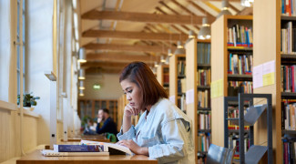 A woman is reading a book in a library