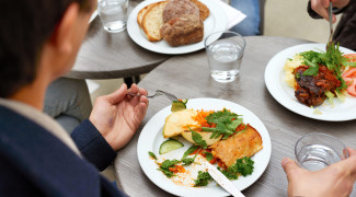 There are some foods on plates and several cups of water on tables