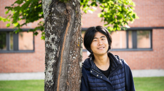 Student standing by a tree