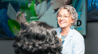 Nainen hymyilee toiselle henkilölle