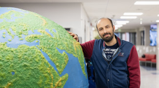 Student leaning on a giant globe