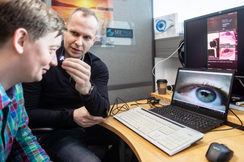 Two men sitting in front of computer screens showing eye-tracking technology.