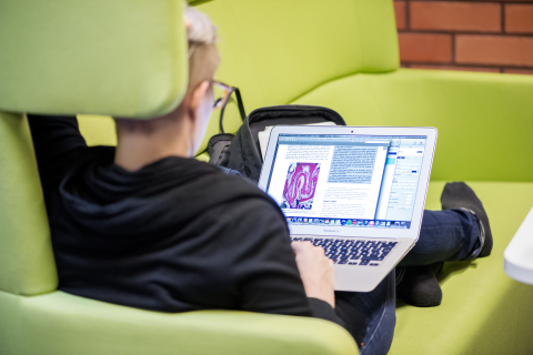 Nuori mies istuu sohvalla ja opiskelee etäyhteyden kautta.