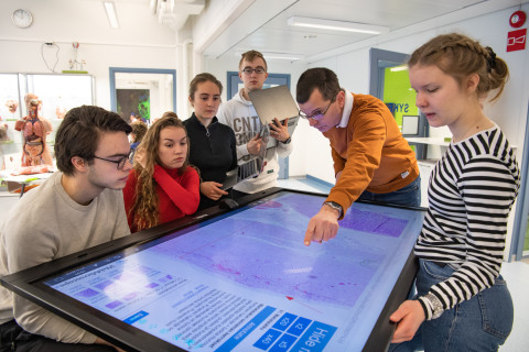 Opettaja esittelee opiskelijoille virtuaalinäytettä kosketusnäytöltä.