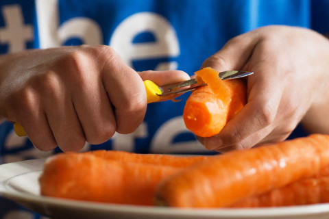 Hands peeling carrots