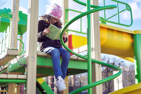 Lapsi lukee leikkipuistossa.