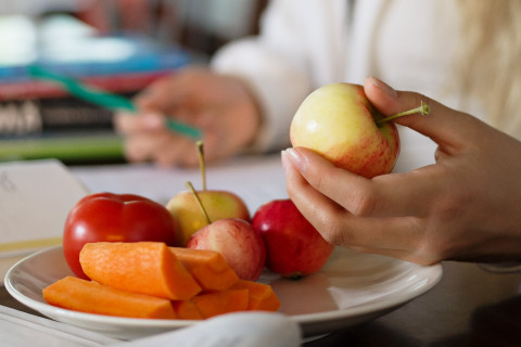 Tyttö pitelee omenaa kädessään.