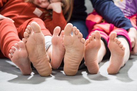 perhe istuu lattialla paljaat jalkapohjat näkyvillä