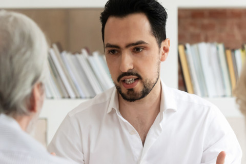 Mies keskustelee ikääntyneen pariskunnan kanssa.