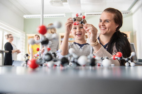 lapsi ja äiti kokoavat molekyylimallia