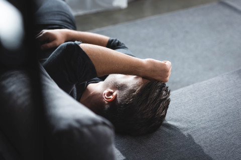 Man with headache lying on sofa