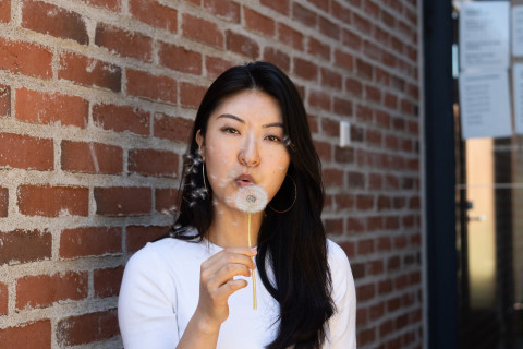 Young woman blowing dandelion seeds.