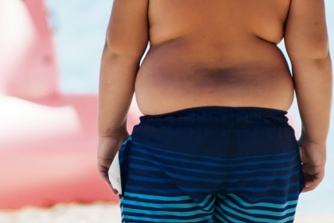 Obese child on a beach.
